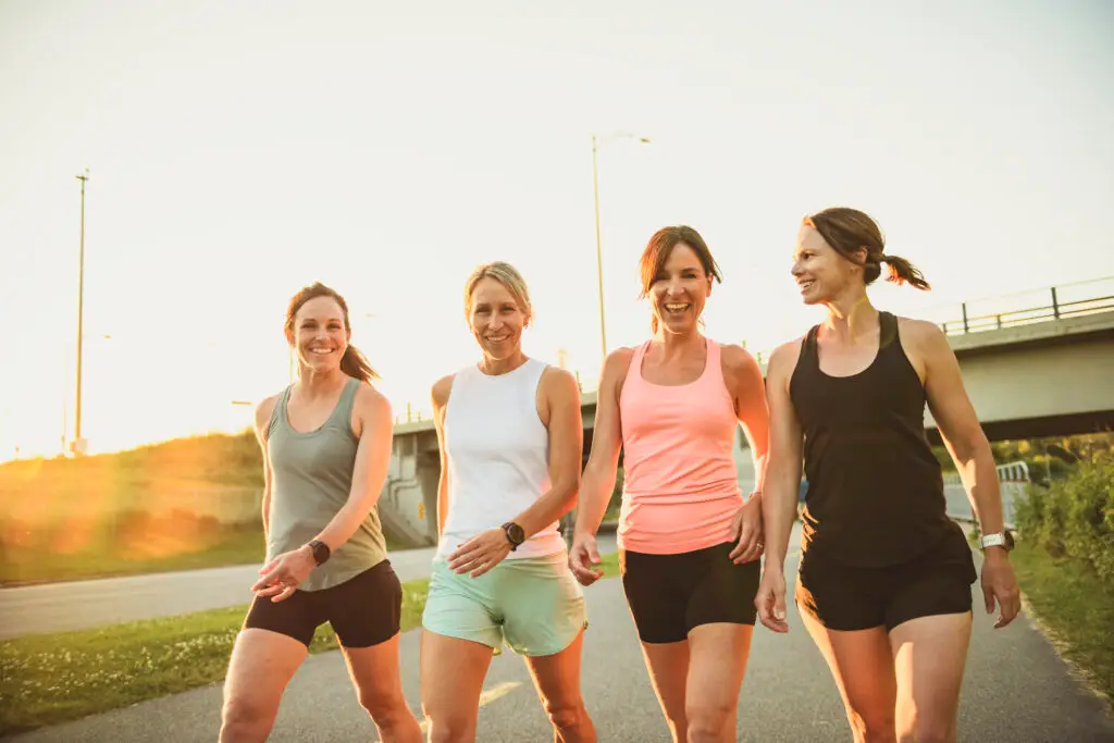 females in sportswear walking together bright sunny park in summer